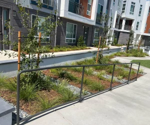 building exterior with railing and plants along a walkway