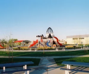 outdoor playground with slides and climbing structures in a grassy park