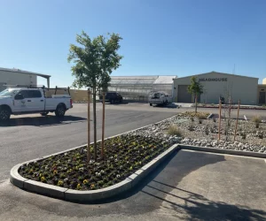 parking lot with landscaping in front of a greenhouse and warehouse building